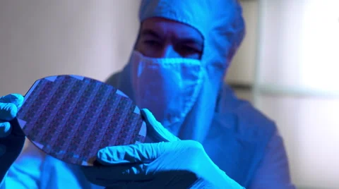 Cleanroom tech checking out a silicon wafer microchip disk 4k Stock Footage 61719300