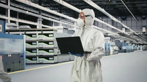 Cleanroom technician tracking semiconductor fabrication lots with laptop Stock Footage 333393510