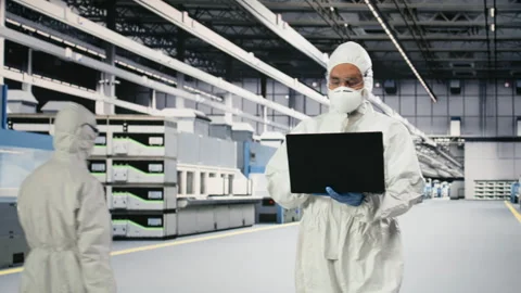 Cleanroom technician tracking semiconductor fabrication lots with laptop Stock Footage 333395442