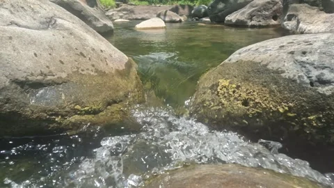 A clear and calm mountain river cascades through rocks Stock-Footage 323149915