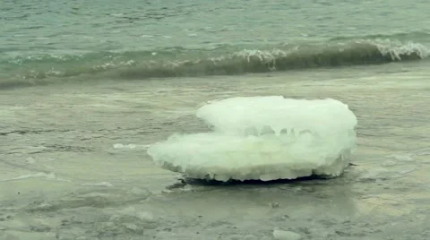 Clear block of ice lying on the sand beach. Winter sea Video stock 55424985