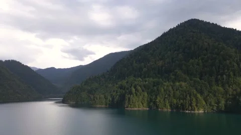 A clear blue mountain lake surrounded by mountain peaks and forest Stock Footage 144645937