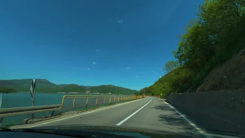 Clear blue sky above winding road beside lake. Balkan, Eastern Europe, POV Video stock 333345285