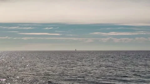 A clear blue sky and a calm sea with a sail on the horizon.  Stock Footage 273178396