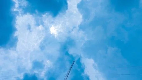 A clear blue sky with cumulus clouds and a communication tower. Stock Photos