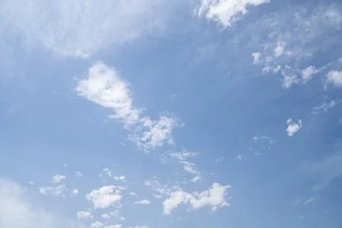 Clear blue sky dotted with small fluffy clouds, natural sky background Stock Photos