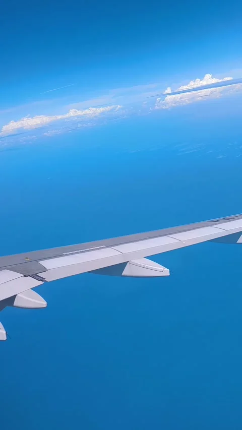 Clear blue sky filled with fluffy clouds, with visible aircraft wing Video stock 312730658