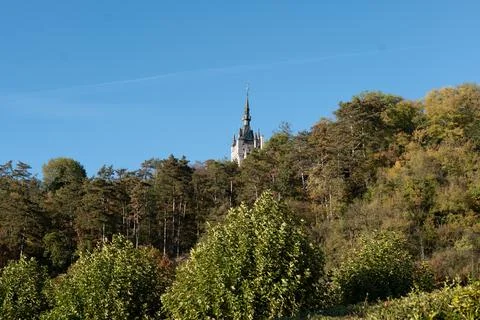 Clear blue sky frames ancient spire above forested hill Foto stock