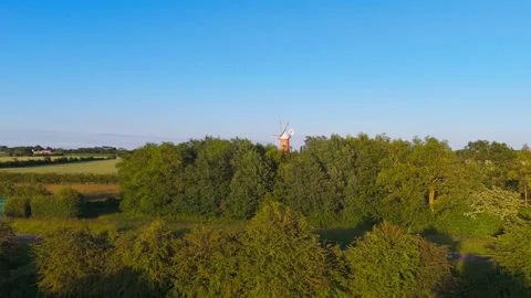 Clear blue sky frames historic windmill on green fields Vidéo 342610481