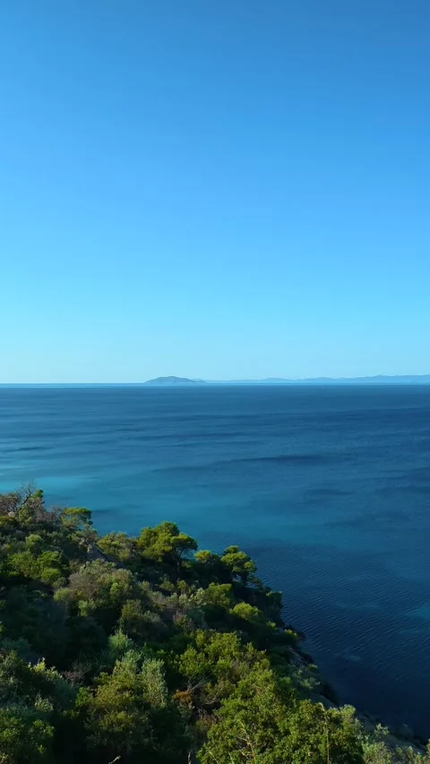 Clear blue sky meets calm ocean waters. Lagomandra, Greece. Vertical Stock Footage 339624121