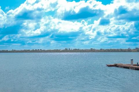 Clear blue sky over tranquil water with wooden dock in daylight Stock Photos