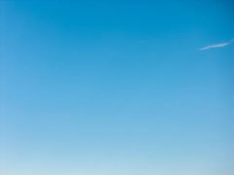Clear blue sky with a smooth gradient and a thin wispy cloud near the top Фото
