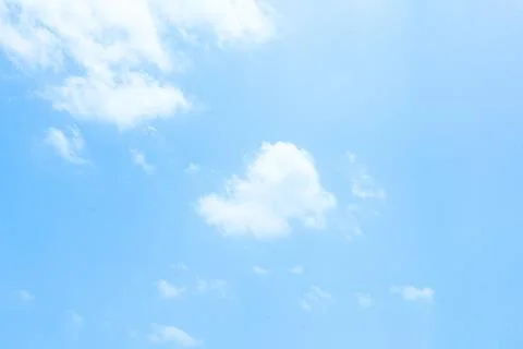 Clear blue sky with soft white clouds floating in peaceful daylight atmospher Stock Photos