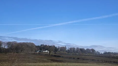 Clear blue sky with wispy clouds above a quiet field Stock Photos