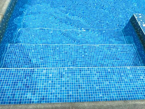 Clear blue swimming pool steps with tile pattern during daytime Stock Photos