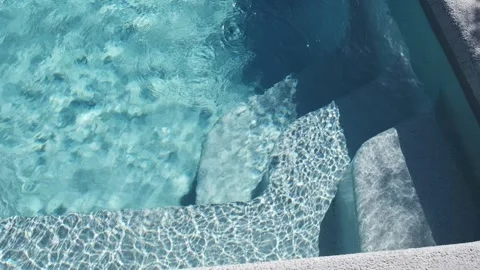 Clear blue water in a private tiled pool with underwater steps and bright sunlig Stock Footage 312019132