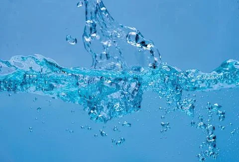 Clear blue water splash with bubbles on blue background Stock-Fotos
