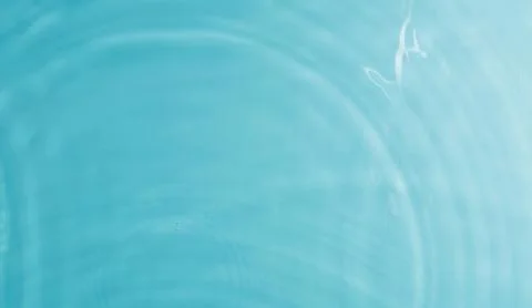 Clear blue water surface with ripples from drops as background Stock Photos