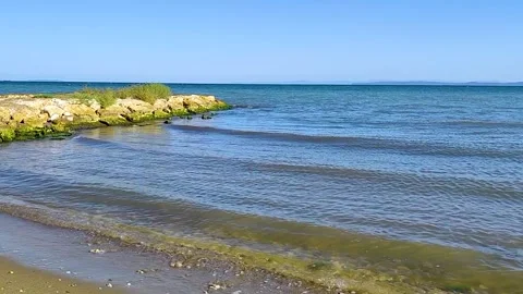Clear Blue Water Waves Gently Lapping a Sandy Beach with Rocky Headland Stock Footage 322691520