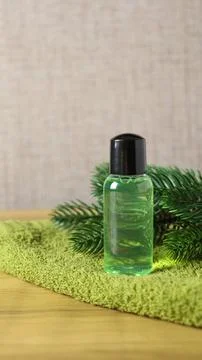 Clear bottle with green liquid placed on green towel next to pine leaves Stock Photos