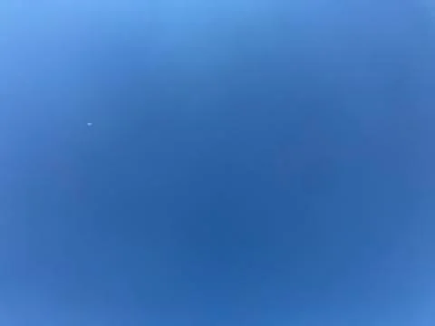 Clear bright blue sky with tiny white dot of airplane in natural light Stock Photos