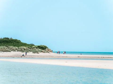 Clear cloudless sky over a beautiful sandy beach. A few people on a sandy beach. Stock Photos