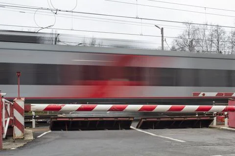 A clear electric train against the background of a closed barrier, road safet Stock Photos