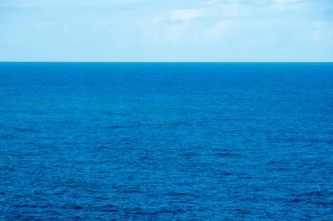 Clear empty ocean with a small flock of birds in the distance Stock Photos