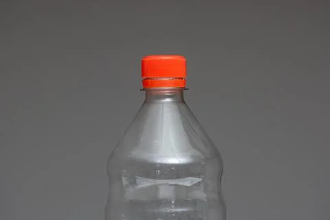 Clear empty plastic bottle with red lid isolated on gray close up detail shot Fotos de archivo