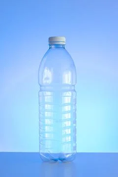 Clear empty plastic bottle with red lid isolated on light blue background ver Fotos de archivo