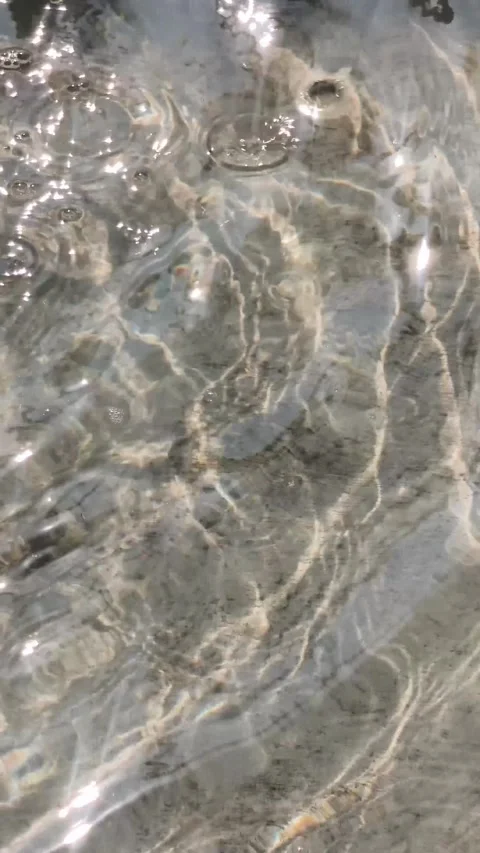 Clear flowing water ripples over textured stone bottom, sunlight caustics a.. Stock Footage 346659365