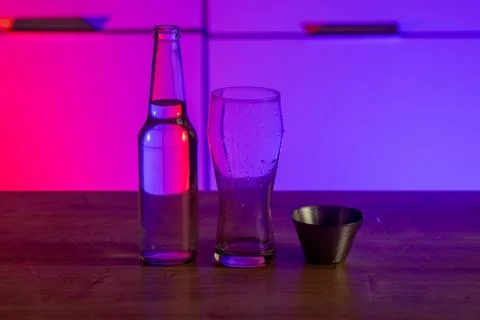 Clear glass bottle empty drinking glass and metal measuring cup on wooden table Stock Photos