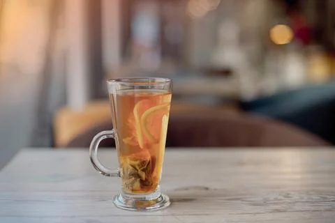 Clear glass cup of tea on table in cafe interior with blurred color background Stock Photos