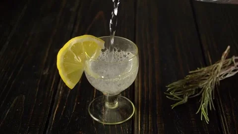 Clear glass with lemon slice filled with sparkling beverage, bubbles rising as Video stock 333591820