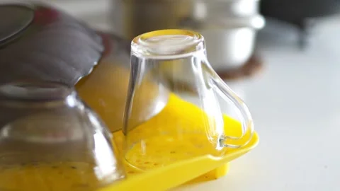 Clear glass mugs drying upside down on a yellow tray Stock Footage 332580358