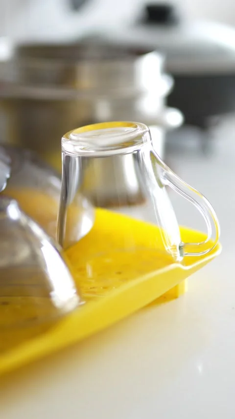 Clear glass mugs drying upside down on a yellow tray Stock Footage 332580360