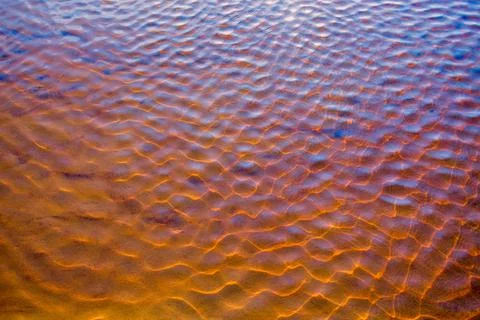 Clear golden water stream pattern with sand waves under it Stock Photos
