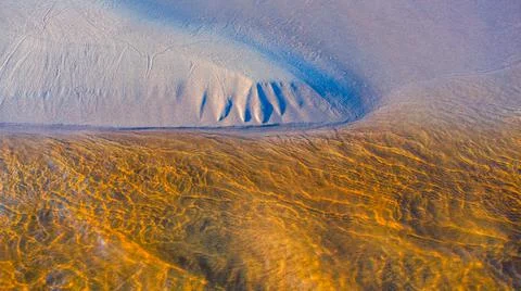 Clear golden water stream pattern with sand waves under it Stock Photos