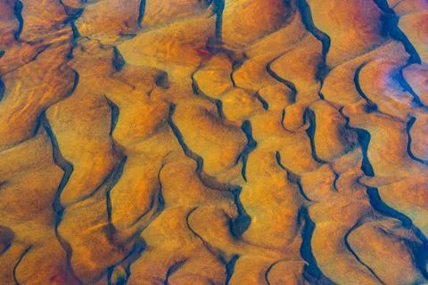 Clear golden water stream pattern with sand waves under it Stock Photos