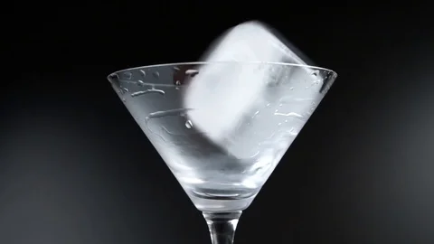 Clear ice cube spinning in a cocktail glass - Slow Motion Stock Footage 126939135