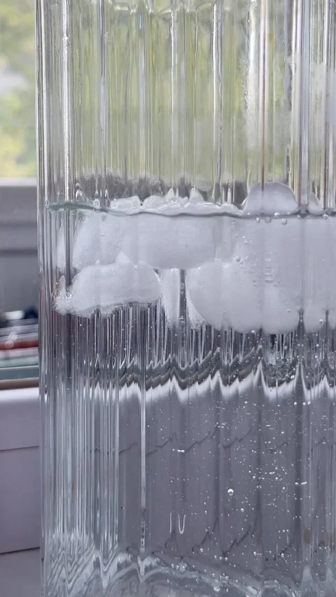 Clear ice cubes floating in glass of water macro video Stock Footage 336506986