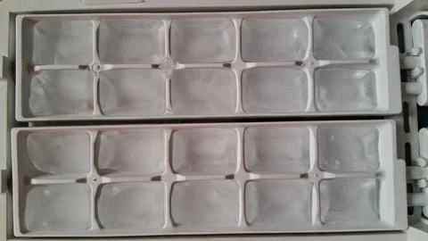 Clear ice cubes sitting inside a white plastic freezer tray Stock Photos