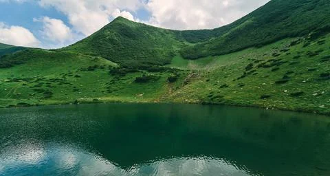 Clear lake against the backdrop of green mountains and blue sky in sunny summ Foto stock
