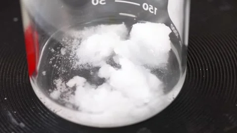 Clear liquid and white solid substances bubbling in a glass beaker, undergo.. Stock-Footage 334326799