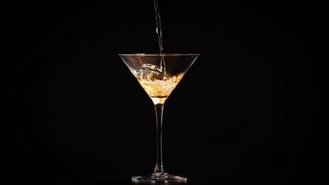 Clear liquid being poured into a martini glass with black background. Stock Footage 332765025