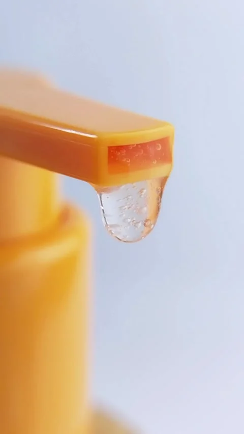 Clear liquid coming out and dripping from orange product packaging. Vertica.. Stock-Footage 336238750