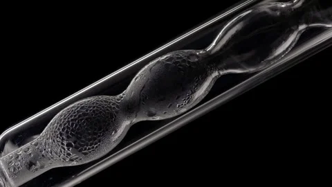 Clear liquid condensing on bulb lab condenser black background Stock Footage 339378600