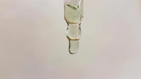 Clear liquid drip from glass eye dropper. Droplet of serum oil Stock Footage 320742969