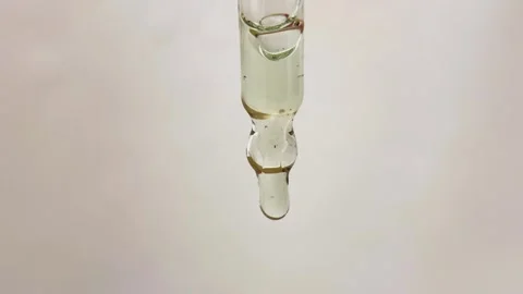 Clear liquid drip from glass eye dropper. Droplet of serum oil Stock Footage 320743026