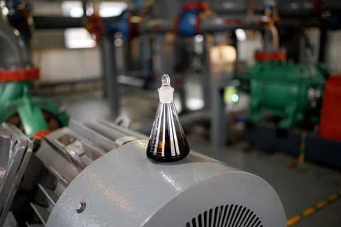 Clear liquid filled laboratory flask with narrow neck resting on industrial Foto stock